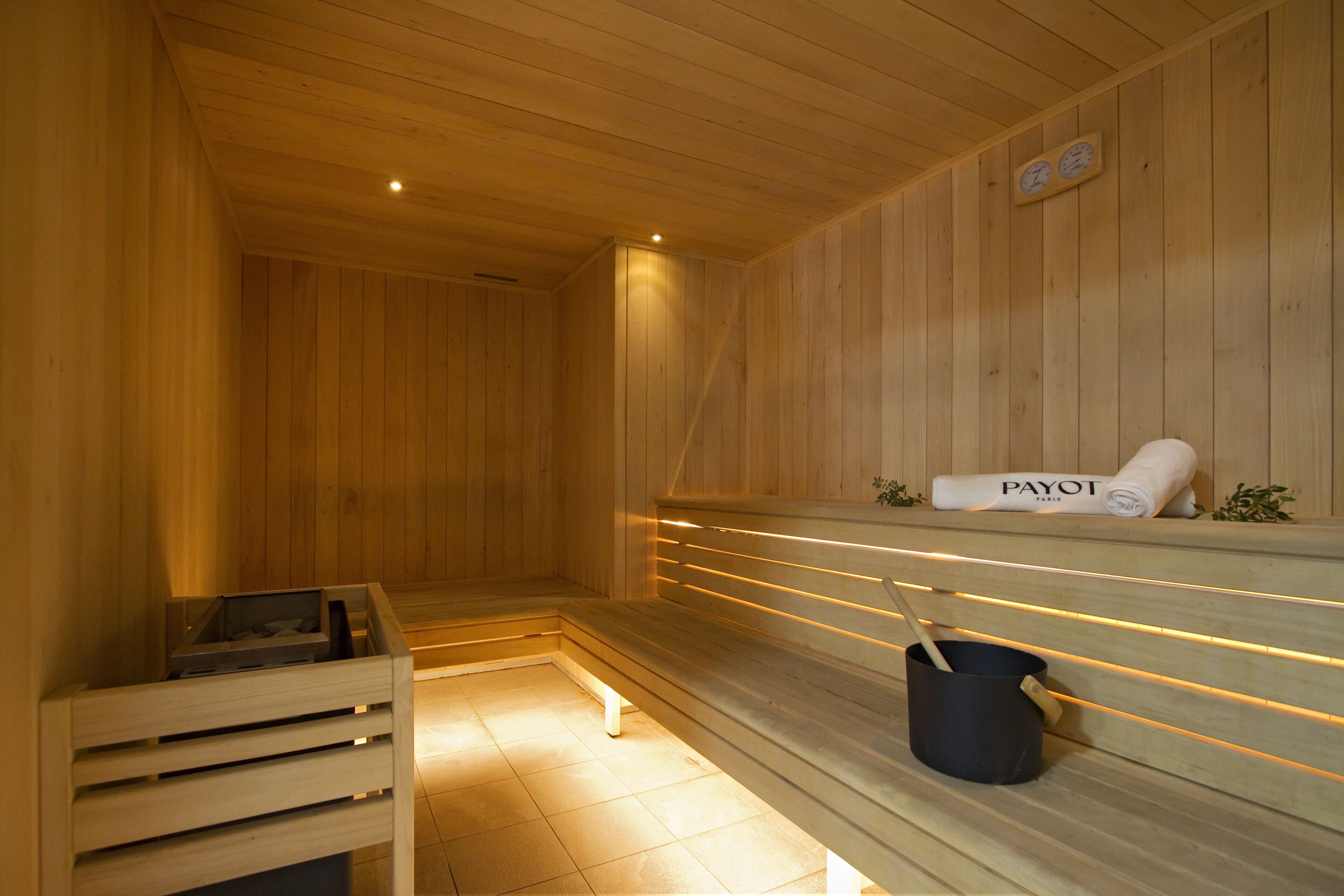A wooden sauna with benches, a towel, and a bucket.