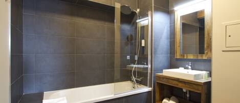 A modern bathroom with a large bathtub, a shower, and a vanity with a mirror.