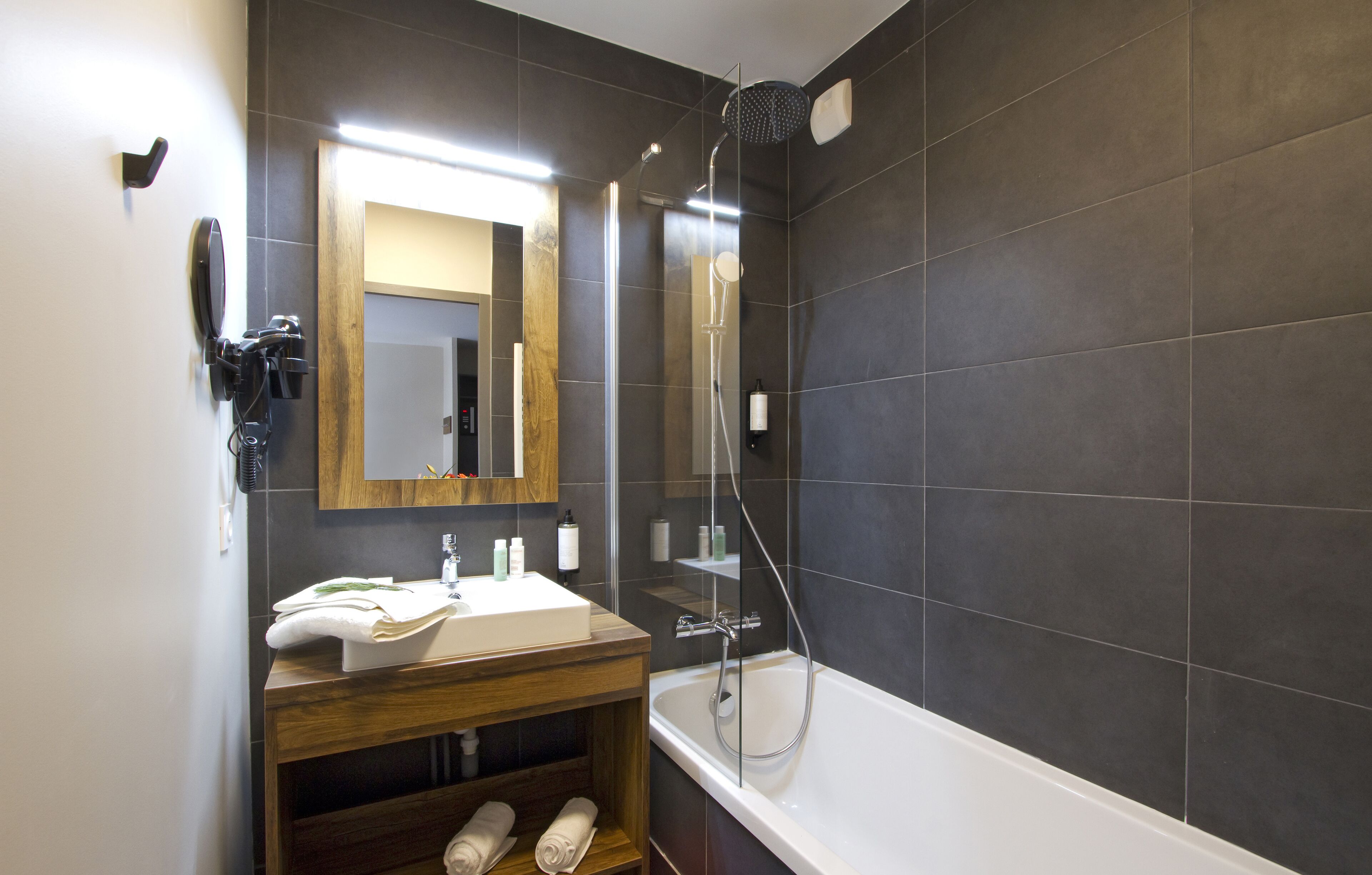 A modern bathroom with a large mirror, a bathtub, and a shower area.