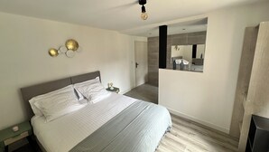 Een moderne slaapkamer met een groot bed, een nachtkastje, een wandlamp en een spiegel.