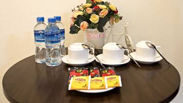 Una mesa con botellas de agua, vasos, cucharas y sobres de café instantáneo.