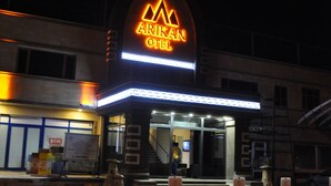 A hotel entrance with a neon sign, a staircase, and a parking area. - Arikan Otel (Pozanti)