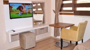 A room with a TV on the wall, a small table, a chair, and a window with curtains. - Arikan Otel (Pozanti)