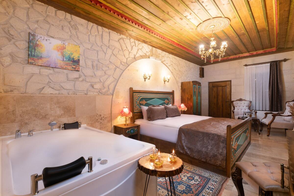 Un dormitorio con una bañera grande, una cama con cabecera de madera y un candelabro.