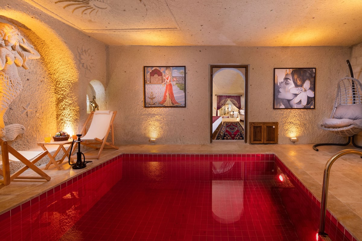 Un área de spa con piscina de baldosas rojas, sillones de madera y obras de arte colgadas en la pared.