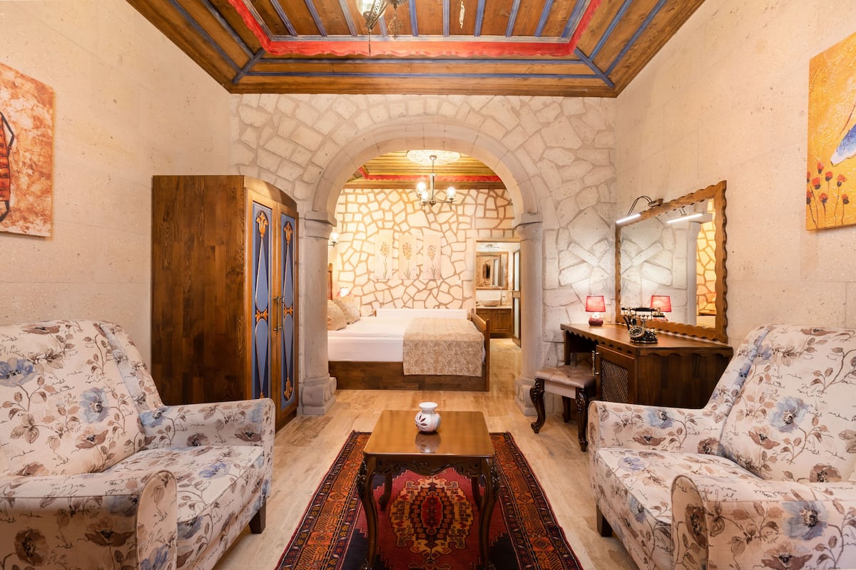 Una habitación acogedora con una cama, dos sofás, una mesa de madera y una pared de piedra.