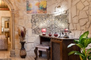 Pareda de pedra com um banco de madeira rústico e uma mesa com abajur e objetos decorativos.