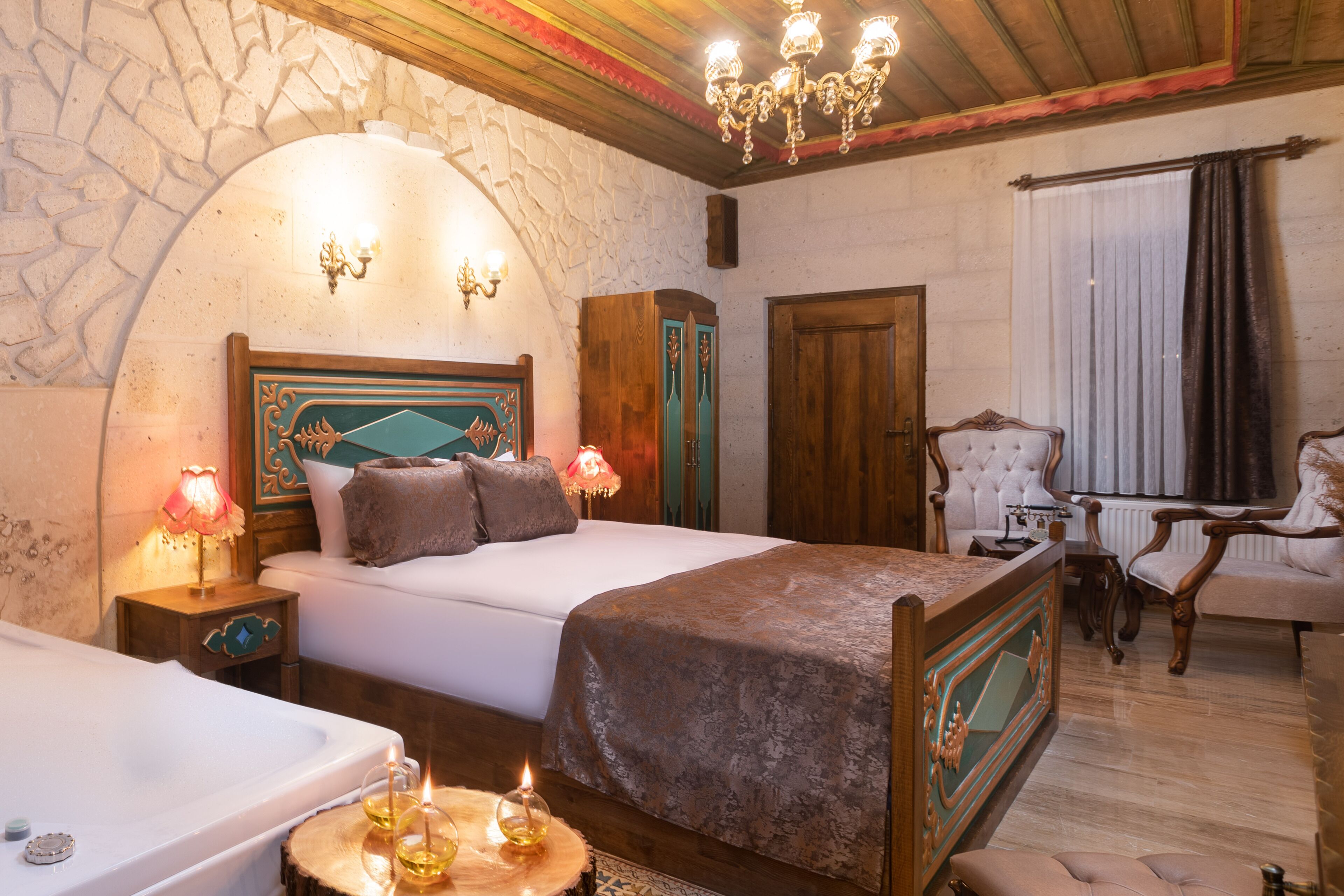 Une chambre à coucher avec un grand lit, une tête de lit en bois, une table de chevet avec une lampe, une armoire en bois, une chaise et une fenêtre avec des rideaux.