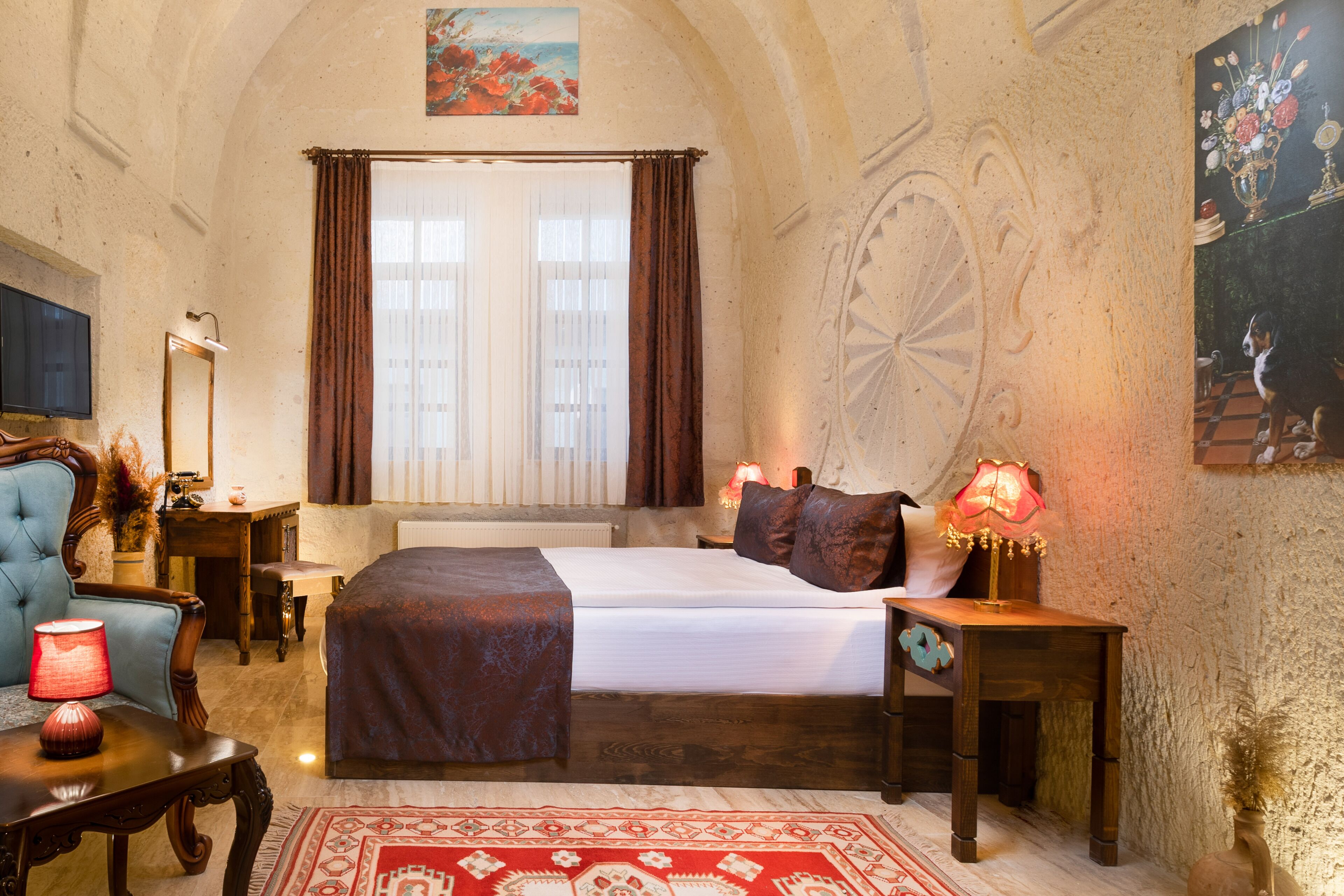 A bedroom with a large bed, a desk, a chair, a lamp, and a painting on the wall.