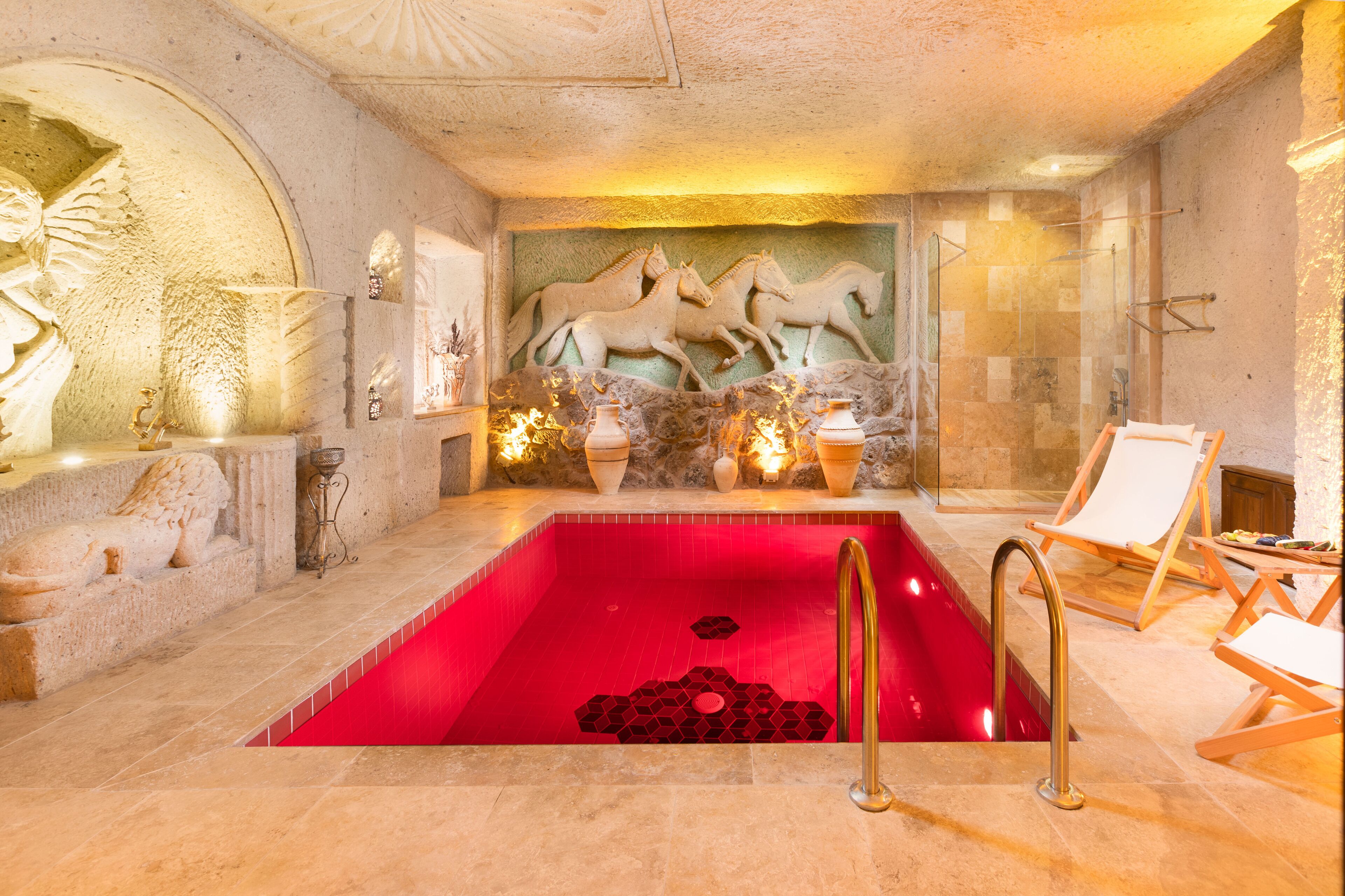 A red pool with a geometric pattern, stone lion sculptures, and a seating area with a white chair.