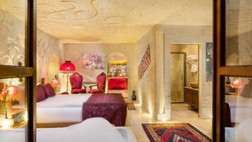A hotel room with a large bed, a sitting area with a red chair, a small table, and a decorative rug.