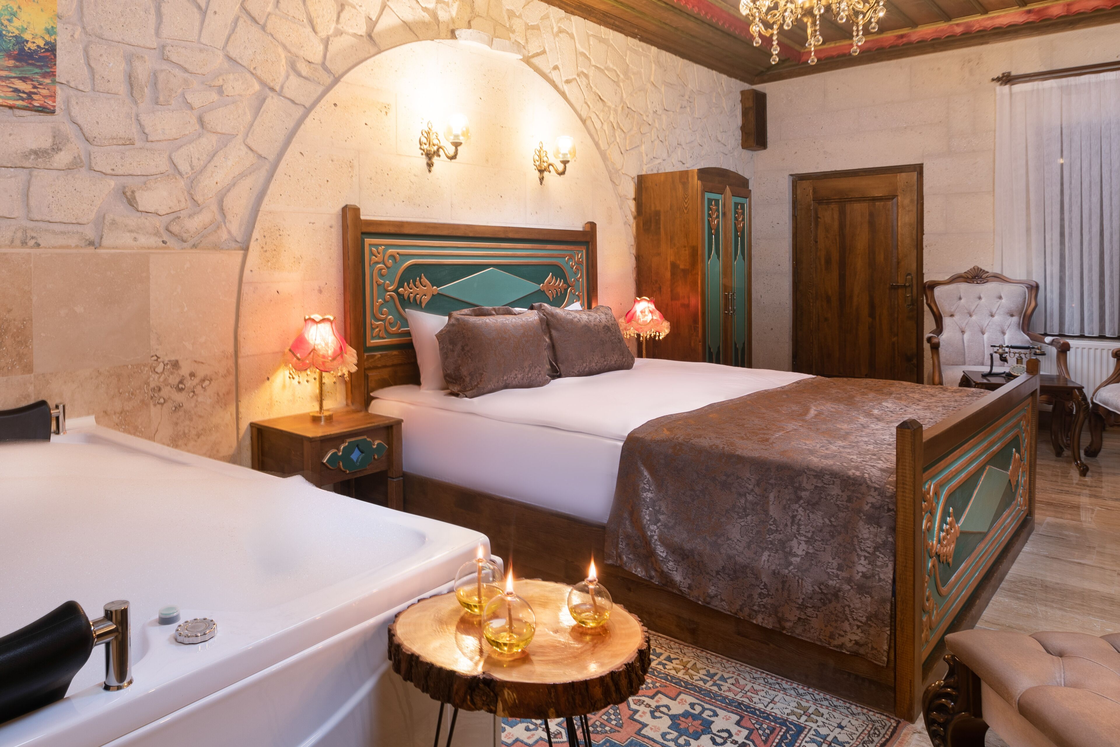 Un dormitorio con una cama grande, un cabecero de madera, una zona de estar con una silla y una bañera.