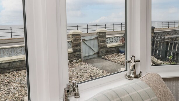 Ein Zimmer mit großem Fenster, das einen Blick auf einen felsigen Garten und die Küste bietet.