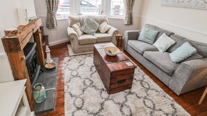 Ein gemütliches Wohnzimmer mit Kamin, zwei Sofas, einem Couchtisch und Blick durch große Fenster nach draußen.