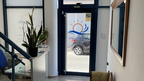 A reception area with a glass door, a reception desk, a chair, and a staircase. - Alojamiento Med The Blue Med. (El Campello)