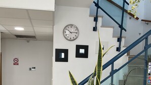 A staircase with glass railings, a clock, and two framed pictures on the wall. - Alojamiento Med The Blue Med. (El Campello)