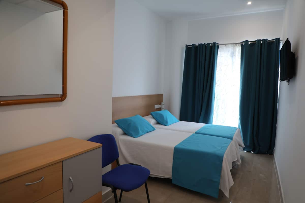 A hotel room with two beds, a wooden dresser, a chair, and a flat-screen TV.