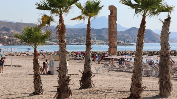 A beach with palm trees, a lifeguard tower, and a rocky shoreline. - Alojamiento Med The Blue Med. (El Campello)