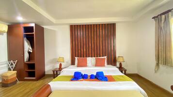 A hotel room with a bed, bedside tables, a wardrobe, and a window with curtains.