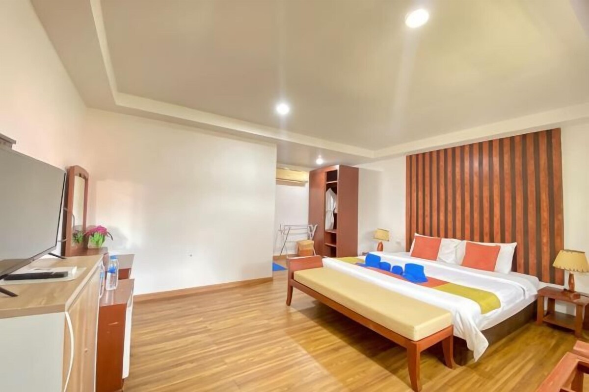A hotel room with a bed, bedside table, desk, and a wardrobe.