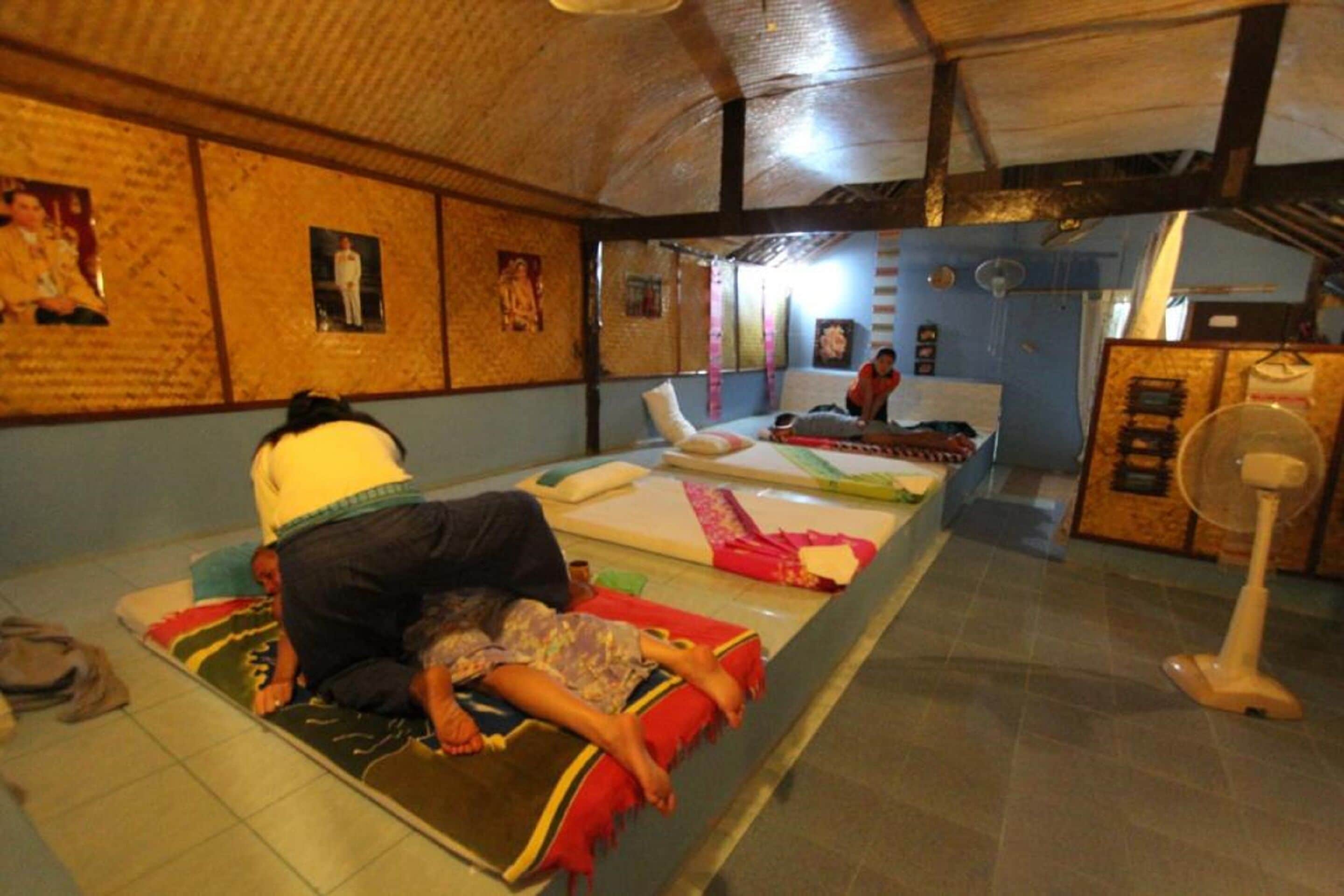 Ein Zimmer mit einem Bett, einem Ventilator und einer Person, die im Bett liegt.
