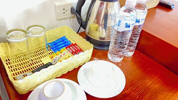 Una bandeja con cafetera, botellas de agua, una cesta de sobres de Nescafé y una taza de café.