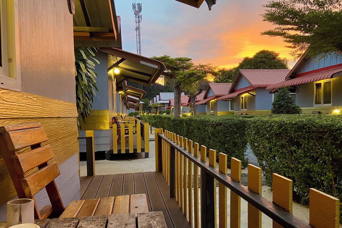 A wooden deck with benches, a railing, and a view of hotel buildings and a tower in the background.