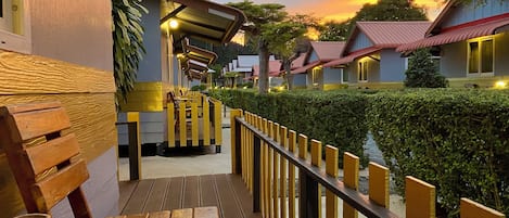 A wooden deck with benches, a railing, and a view of hotel buildings and a tower in the background.