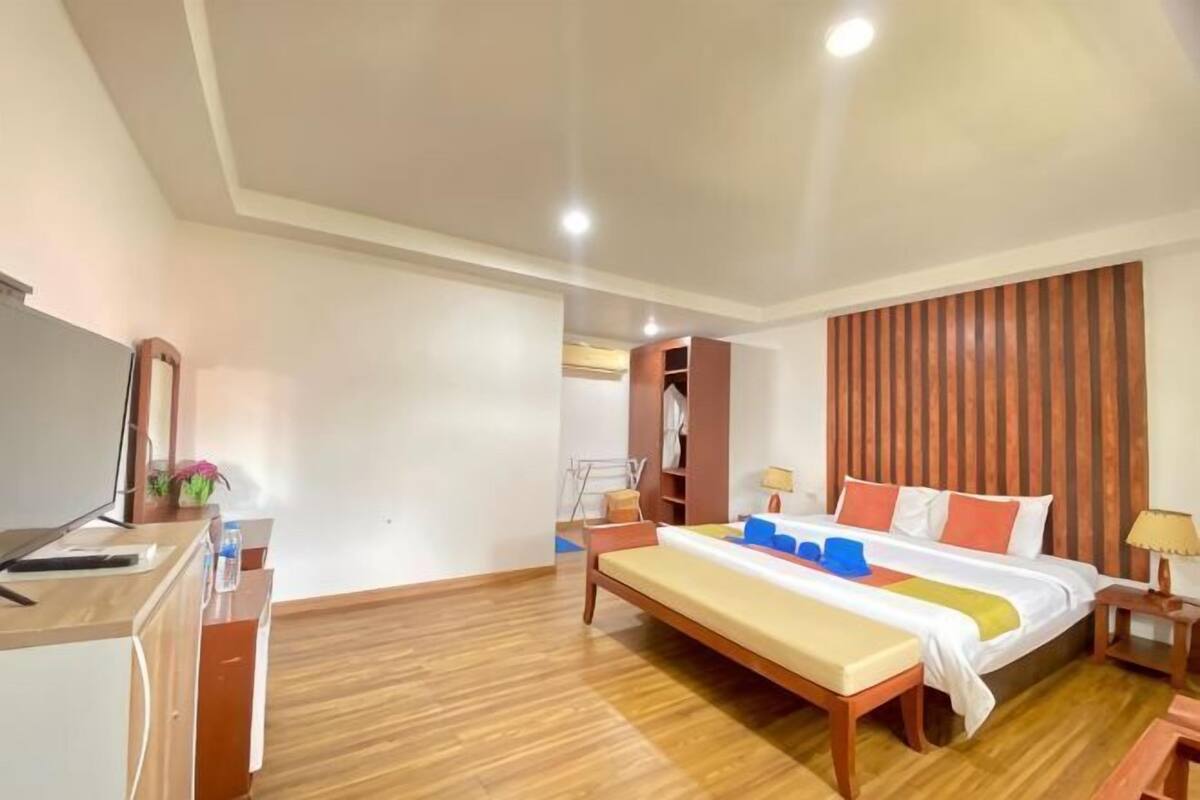A hotel room with a bed, bedside table, desk, and a wardrobe.