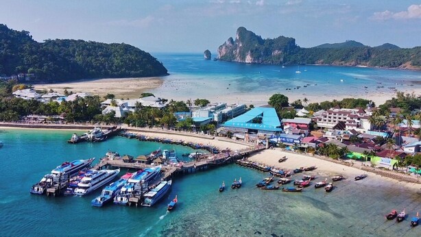 An aerial view of a coastal area with a marina, boats, and buildings.