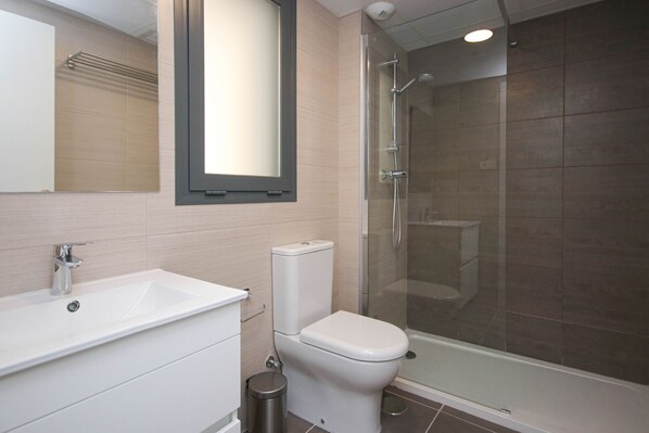 Une salle de bain équipée d’un lavabo, de toilettes et d’une douche à parois de verre.