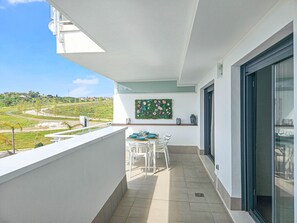 Un balcon avec une table dressée pour le dîner, un mur végétal en guise de décoration et une vue sur un paysage vallonné.