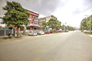 Vista de la calle con coches aparcados, una motocicleta y un edificio con un cartel que dice 'HOTEL ELITE PEAK'.