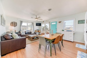 Un salon comprenant un canapé, une table à manger, des chaises, un ventilateur de plafond et un téléviseur.