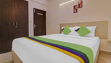 A hotel room with a large bed, a wooden wardrobe, and a door with a handle.