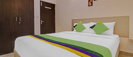 Habitación de hotel con una cama grande, un armario de madera y una puerta con manija.