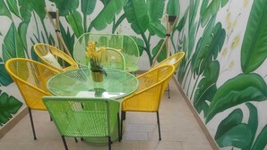 A dining area with a green table and yellow chairs, surrounded by a wall with a large plant mural.