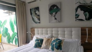 A bedroom with a large bed, a headboard, and artwork on the wall.
