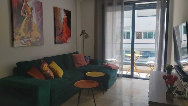 A modern living room with a green sofa, two small round tables, and artwork on the walls.