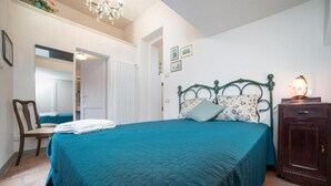 A bedroom with a bed, a chair, a dresser, and a chandelier. - Ivana Le Case di Angelina (Farigliano)