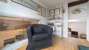 A modern living room with a dark leather sofa, a chandelier, a fireplace, and a bookshelf with framed pictures. - Ivana Le Case di Angelina (Farigliano)