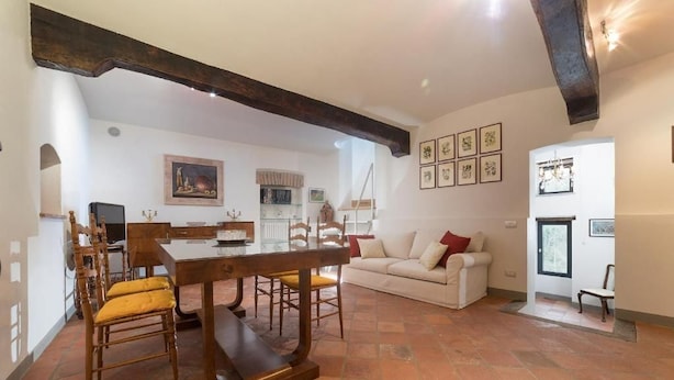 A dining area with a wooden table and chairs, a white sofa, and a fireplace. - Ivana Le Case di Angelina (Farigliano)