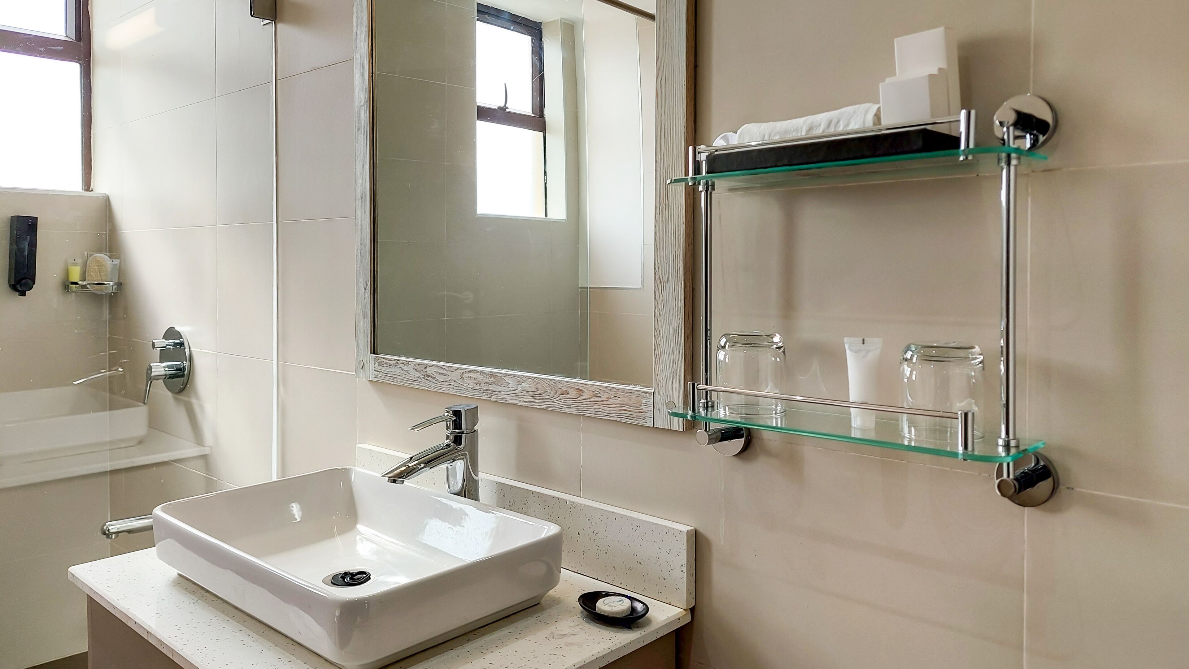 A bathroom with a white sink, a mirror, and a glass shelf with toiletries.