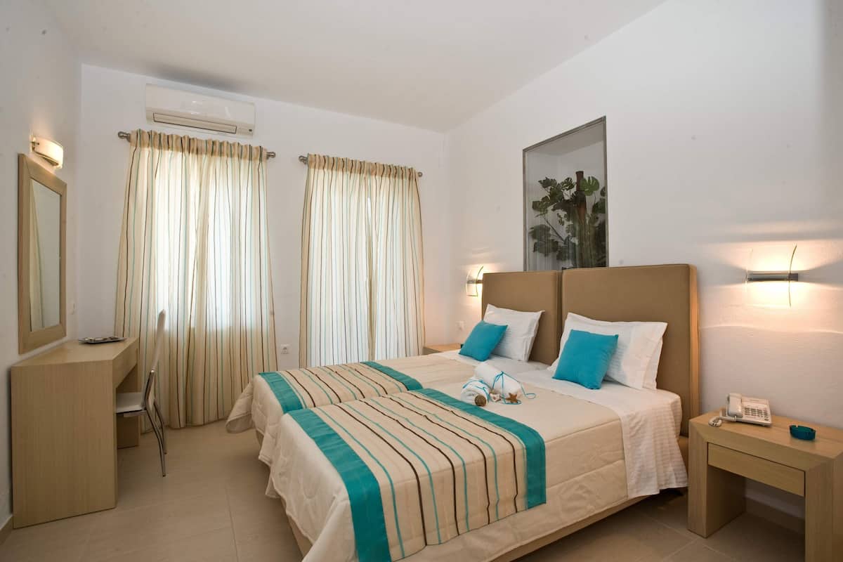 A hotel room with a bed, bedside tables, a desk, and a chair.