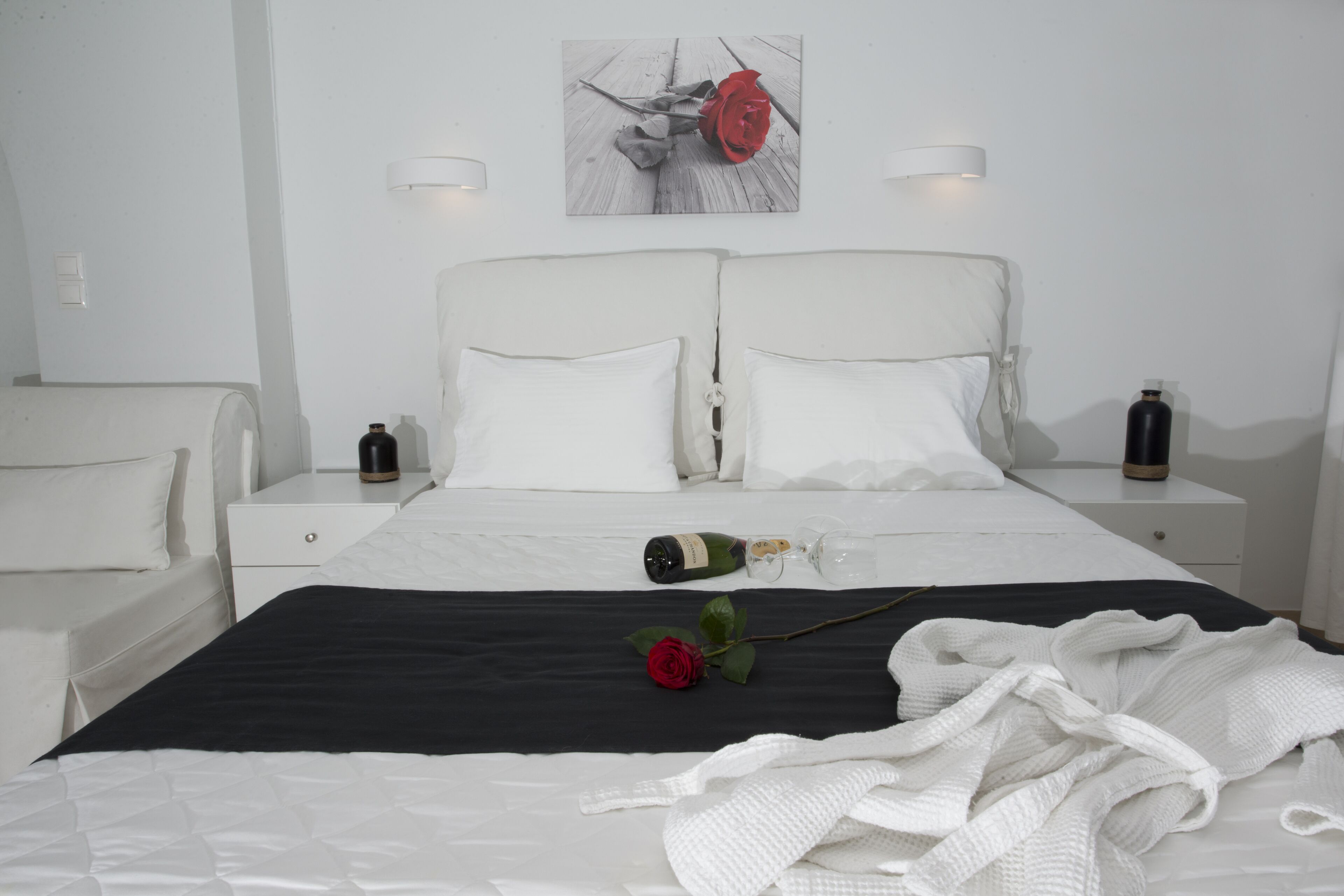 A neatly arranged bedroom with a large bed, two bedside tables, a nightstand, and a wall-mounted light fixture.