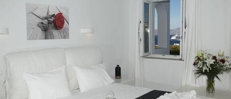 Una habitación de hotel con una cama, una botella de champán, una copa, una rosa roja y un jarrón de flores.