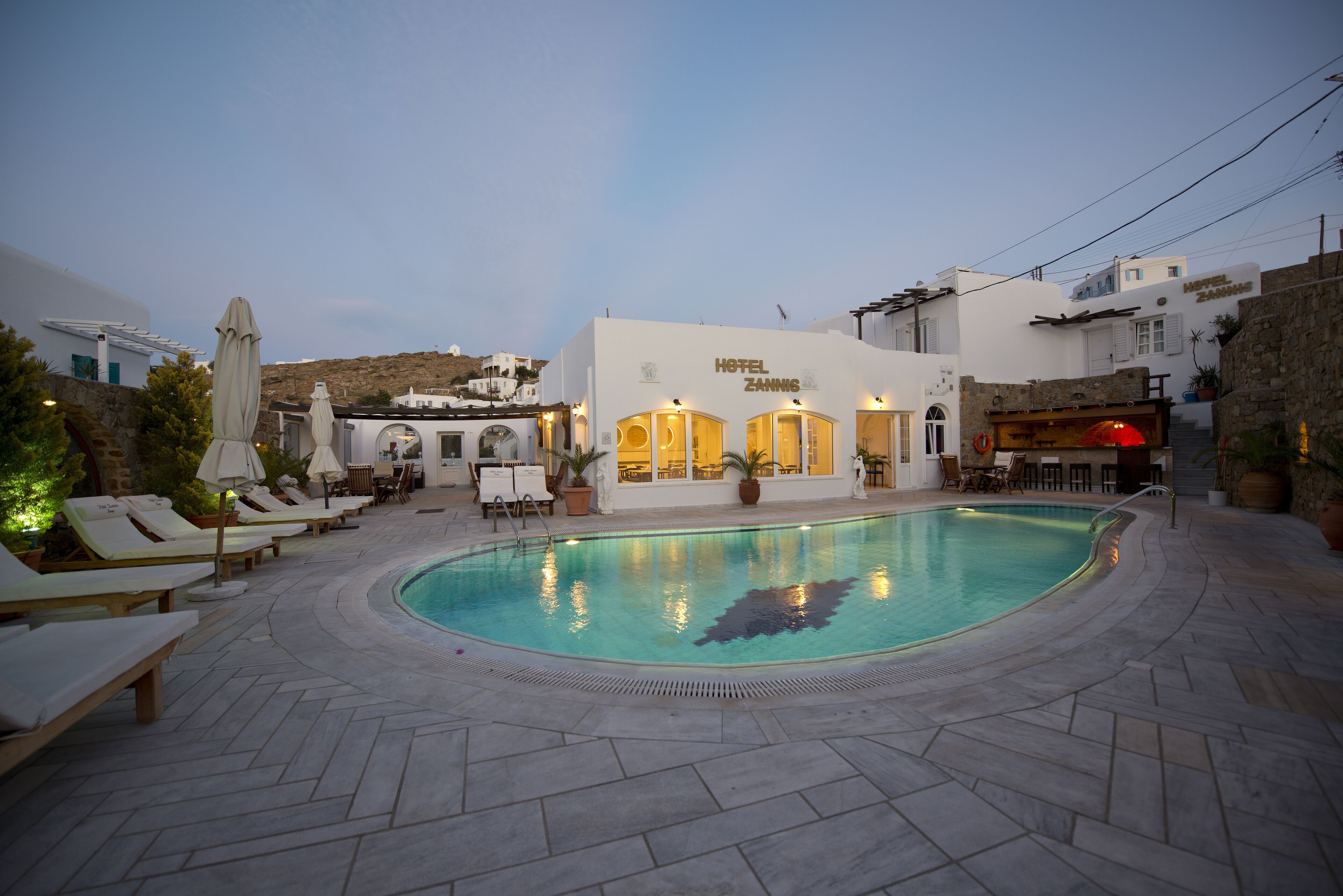 A hotel with a swimming pool, lounge chairs, and outdoor seating.