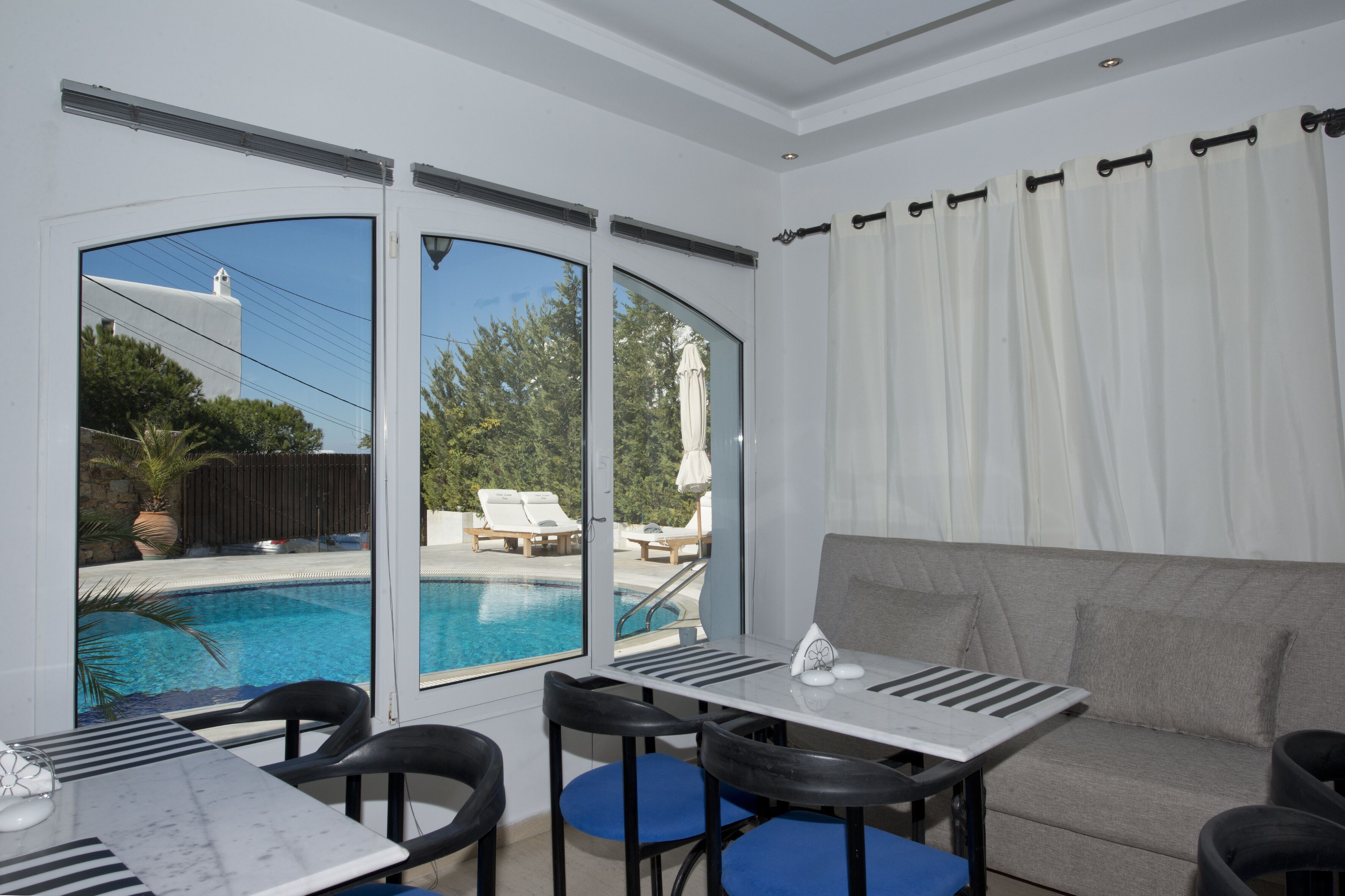 A room with a pool view, a sofa, and a table with chairs.