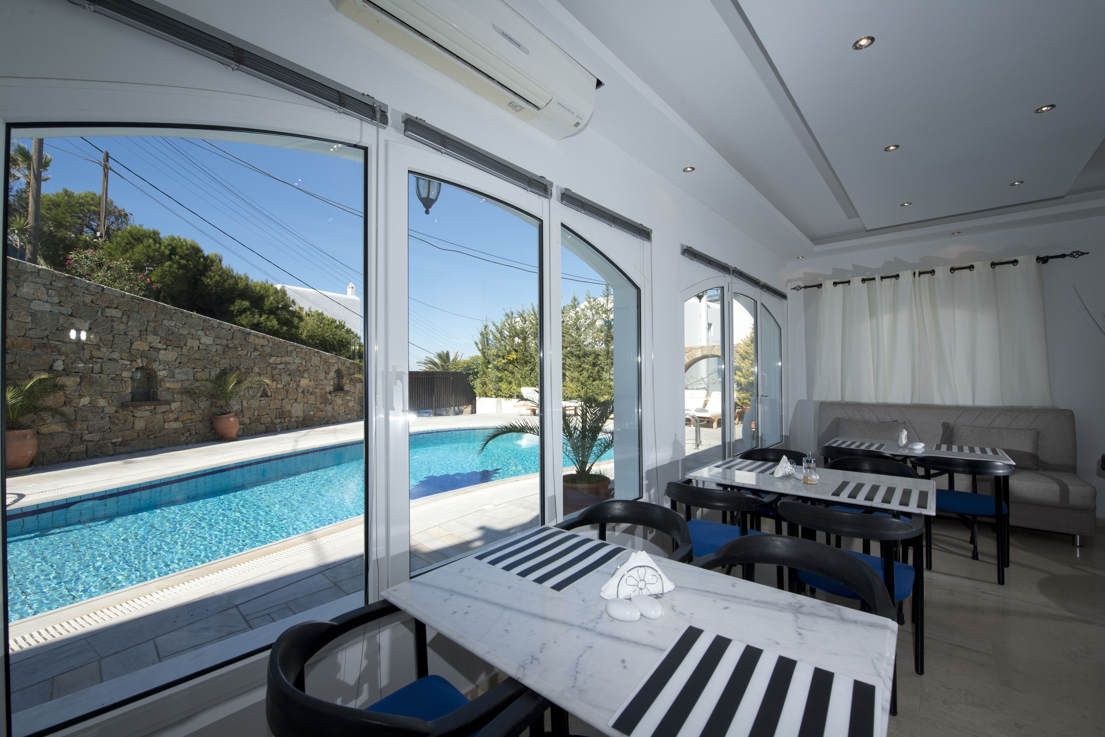 A poolside dining area with a view of the pool, stone wall, and outdoor seating.