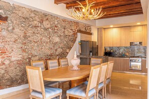 Un espace repas avec un mur en pierre, une table en bois et des chaises.